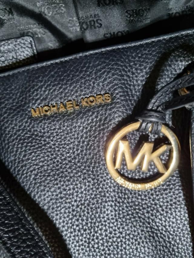 Michael kors leather tote bag (Category: Tote Bags) located in Manila. Submitted by onlinesmartshopping12 (Listing ID 1468781586, Image 3). Description: michael kors black - Stylish design - Made with durable leather. - Black Michael Kors tote bag. Features a zip closure, gold-tone hardware, and the MK logo. The bag has double handles and a textured leather exterior. The interior lining is black. The bag has a rectangular shape with a flat base. 