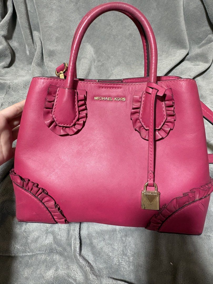 Michael Kors Mercer Gallery (Category: Luxury Bags & Wallets) located in Baguio. Submitted by aella_nyx (Listing ID 1468759800, Image 2). Description: The Michael Kors Mercer Gallery bag features a vibrant fuchsia pink color, structured silhouette, double top handles, and decorative ruffle details on the front and bottom corners. It also comes with a detachable shoulder strap for versatile carrying options. The bag is in heavily used condition, s