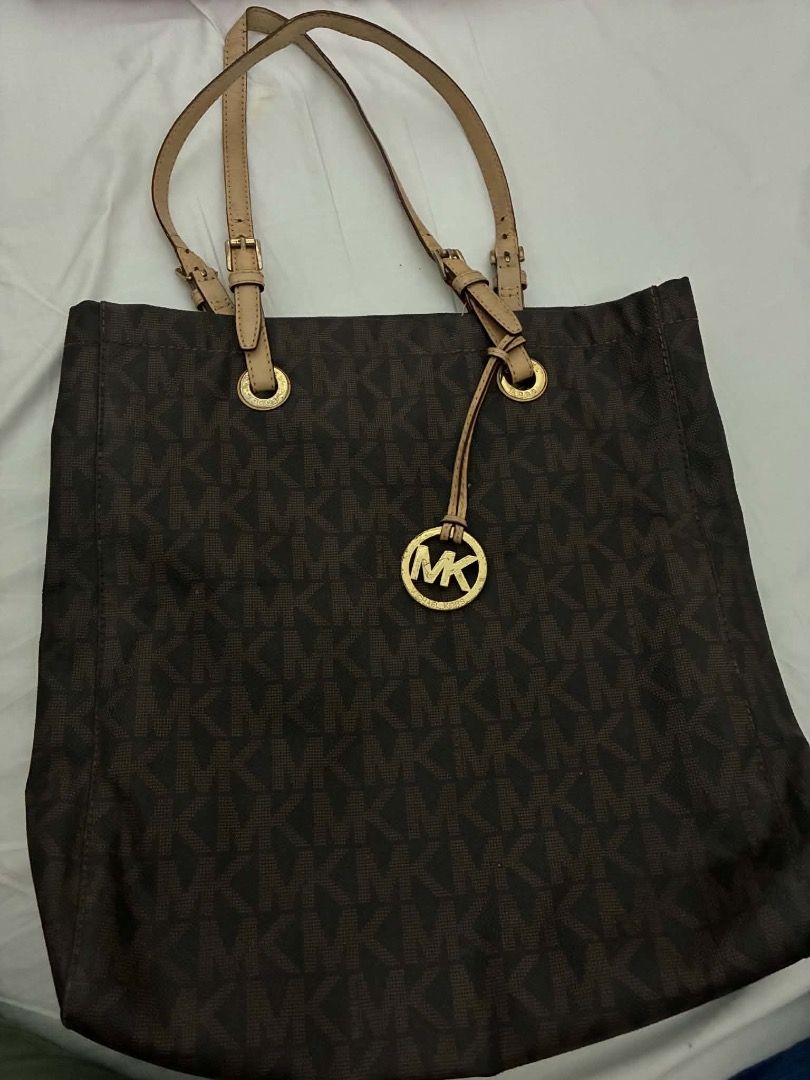 Michael Kors MK Monogram Brown Tote Bag (Category: Tote Bags) located in Manila. Submitted by kissa.1890 (Listing ID 1468887594, Image 1). Description: - Brown tote bag with all-over MK monogram print - Dual tan leather shoulder straps with adjustable buckles - Features a chic round gold-tone metal MK logo charm on the front - Structured shape with a clean fabric exterior - Everyday size, perfect for books, a laptop, or daily essentials - Sturdy 