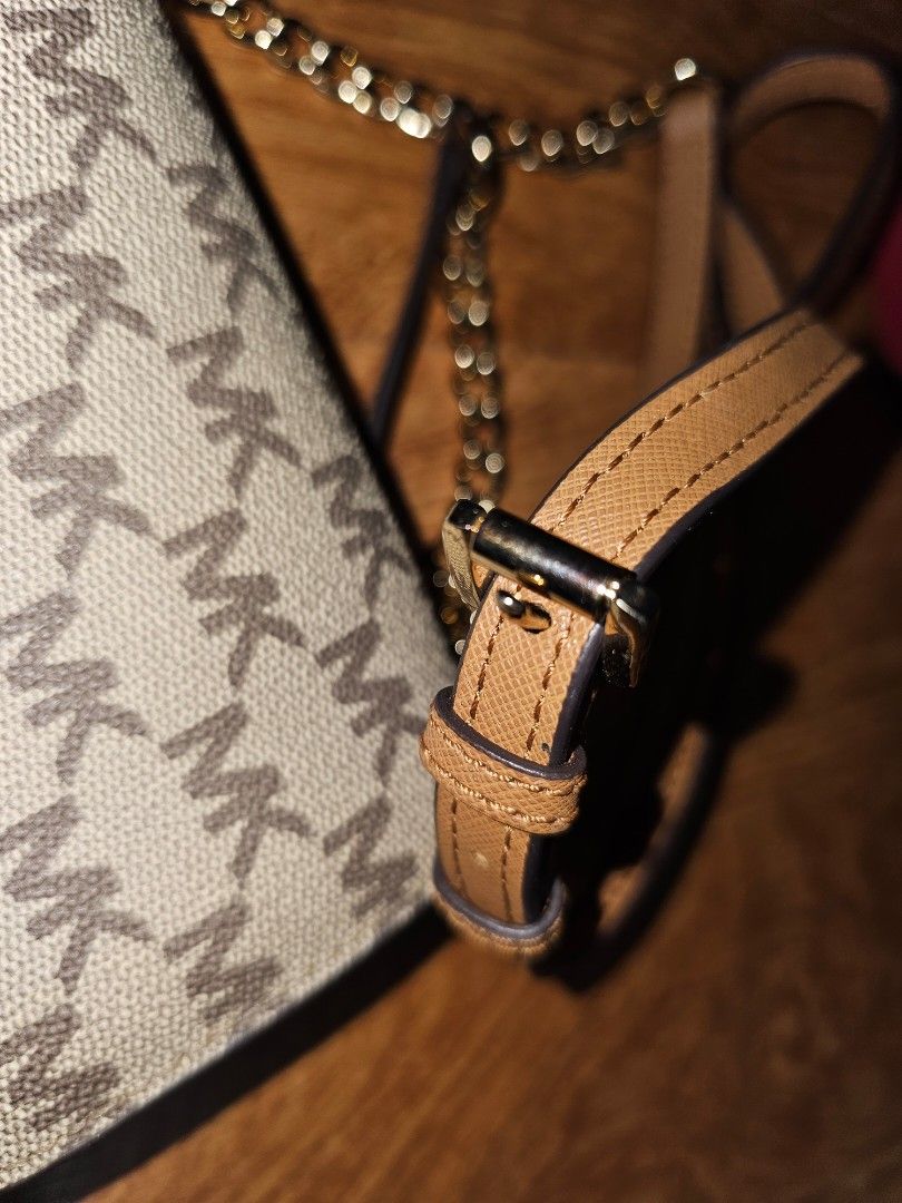 Michael Kors MK Monogram Crossbody Bag Tan (Category: Luxury Bags & Wallets) located in Quezon City. Submitted by findsbydavie (Listing ID 1468822169, Image 2). Description: Michael Kors crossbody bag with the classic MK monogram pattern across the canvas body. Tan leather strap featuring contrast stitching and an adjustable metal buckle. Gold-toned chain accents connect the strap to the bag. Gold lettering spelling out Michael Kors centered on t
