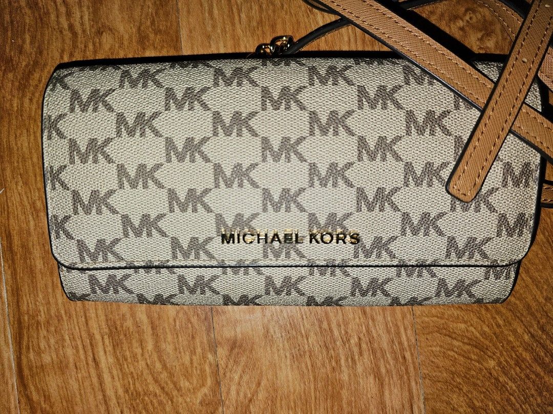 Michael Kors MK Monogram Crossbody Bag Tan (Category: Luxury Bags & Wallets) located in Quezon City. Submitted by findsbydavie (Listing ID 1468822169, Image 1). Description: Michael Kors crossbody bag with the classic MK monogram pattern across the canvas body. Tan leather strap featuring contrast stitching and an adjustable metal buckle. Gold-toned chain accents connect the strap to the bag. Gold lettering spelling out Michael Kors centered on t