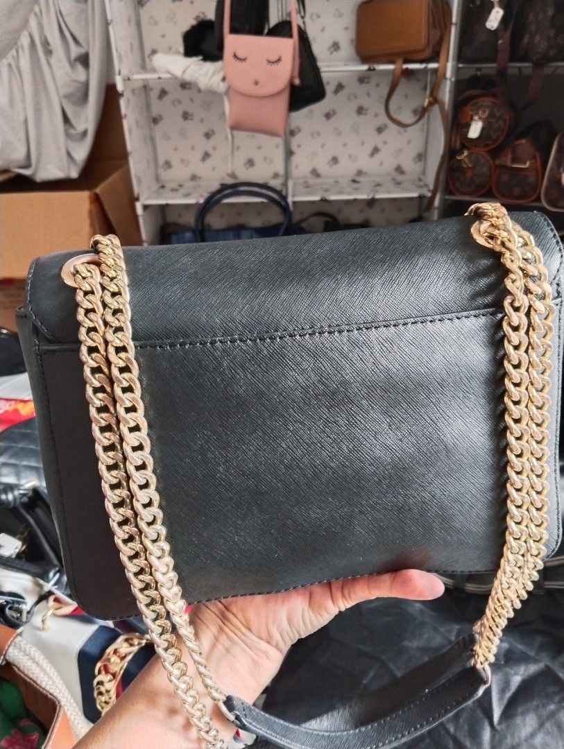 Michael Kors Tina Medium Shoulder Flap Bag] (Category: Luxury Bags & Wallets) located in Manila. Submitted by switruby (Listing ID 1468866791, Image 2). Description: Material: Black Saffiano Leather, known for its durable, scratch-resistant crosshatch texture. [1, 2] Hardware & Features: Polished gold-tone push-lock closure engraved with the brand name, matching gold-tone chain-link shoulder straps with integrated leather handles, and a clean mag