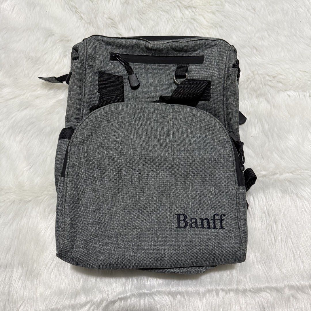 Mini Banff Grey Backpack (Category: Backpacks) located in Pasig City. Submitted by mommy_n_me_closet (Listing ID 1468792741, Image 1). Description: - Colour: Grey heathered with Banff embroidery - Interior: Bright red lining with built-in organizer compartments - Exterior: Secure zipped pockets, top grab handles, and adjustable shoulder straps - Extras: Side mesh pockets equipped with drawstring cords - Condition: Some slight staining visible aro