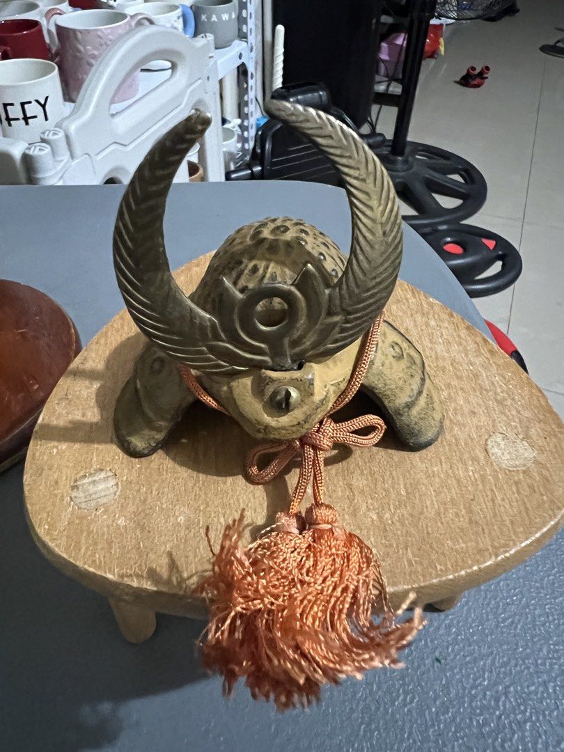 Miniature Samurai Helmet Japanese Decor Display (Category: Figurines & Statues) located in Manila. Submitted by ajdfinds (Listing ID 1468752928, Image 1). Description: - Set of 2 decorative miniature samurai helmets on wooden stands - Piece 1: Antique gold finish with crescent horns and an orange tassel - Piece 2: Classic black textured finish with golden horns and a beige braided cord - Solid build with intricate, well-crafted details - Ideal fo