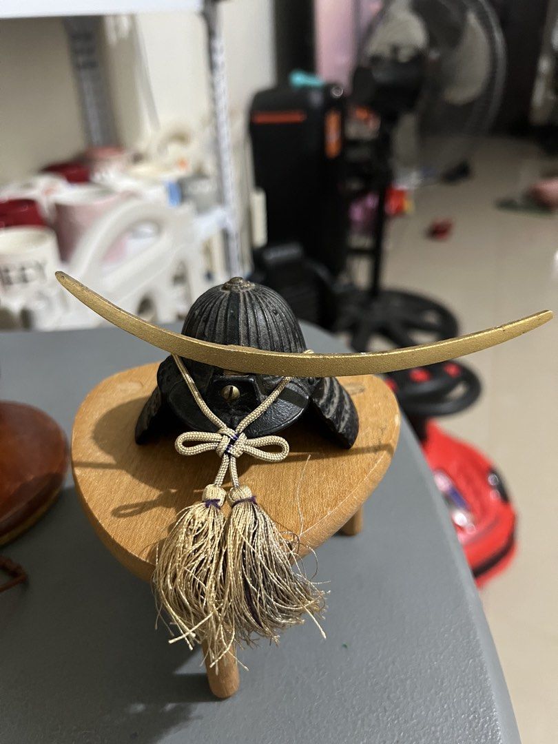 Miniature Samurai Helmet Japanese Decor Display (Category: Figurines & Statues) located in Manila. Submitted by ajdfinds (Listing ID 1468752928, Image 3). Description: - Set of 2 decorative miniature samurai helmets on wooden stands - Piece 1: Antique gold finish with crescent horns and an orange tassel - Piece 2: Classic black textured finish with golden horns and a beige braided cord - Solid build with intricate, well-crafted details - Ideal fo