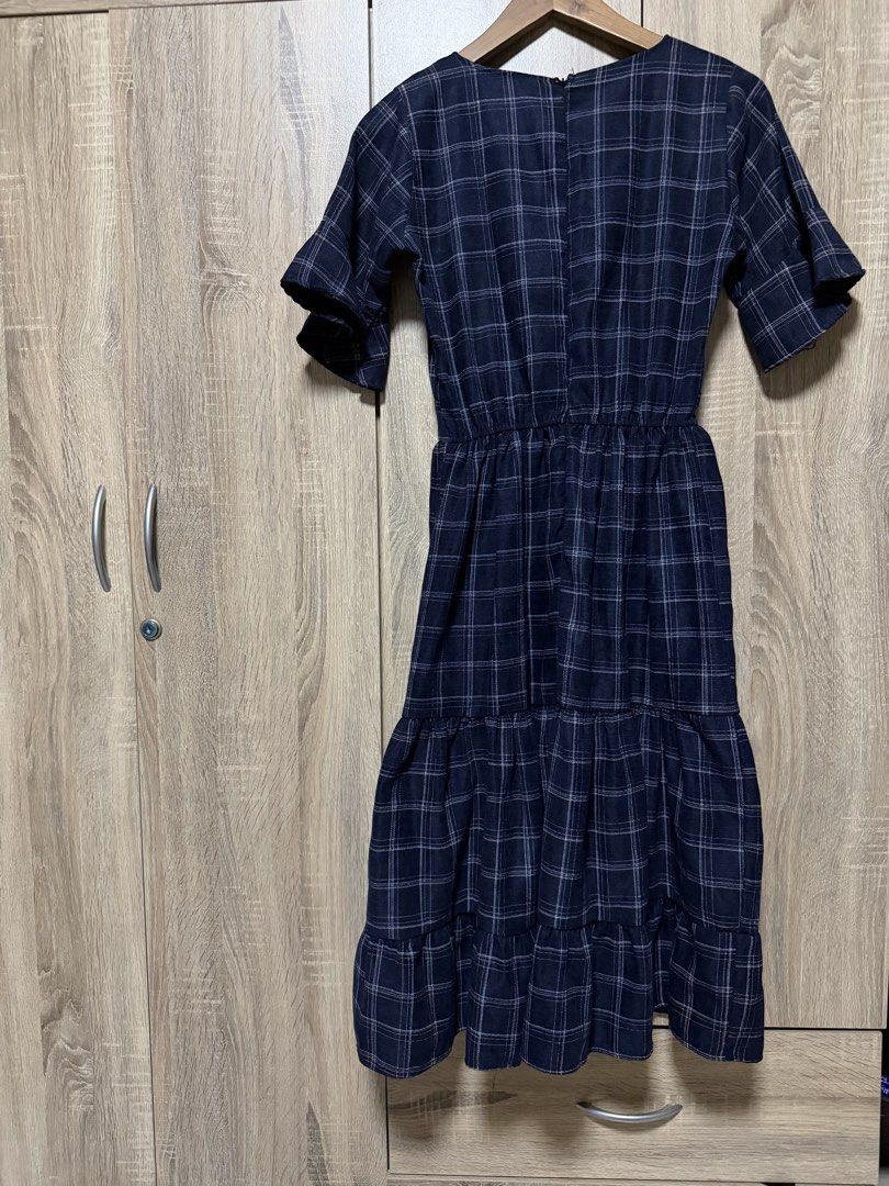Navy Blue Plaid Midi Dress (Category: Dresses) located in Bulacan. Submitted by relove.re (Listing ID 1468719961, Image 2). Description: Elegant and classy with a timeless plaid pattern! 💙 Size: XS to S ✔️ Navy blue with white checkered design ✔️ Flattering V-neckline ✔️ Stylish flutter sleeves ✔️ Defined waist for a feminine silhouette ✔️ Tiered skirt for a flowy, graceful look ✔️ Back zipper closure Perfect for casual outings, office wear, chu