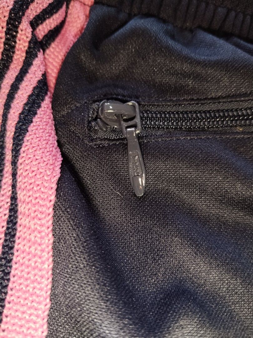 Needles Track Pants Black Pink Size S (Category: Joggers) located in Pasig City. Submitted by loveforlux_2025 (Listing ID 1468784477, Image 3). Description: - Brand: Needles (Nepenthes) - Color: Black with pink side stripes - Size: Small - Details: Embroidered butterfly logo on left thigh, elastic drawstring waistband, and zippered side pockets - Material: 100% Polyester - Origin: Made in Japan - Condition: Clean overall, style code IN933.