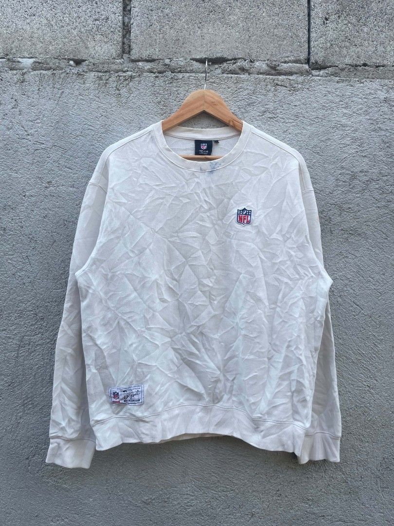 NFL Team Apparel White Crewneck Sweatshirt Medium (Category: Coats, Jackets and Outerwear) located in Banga. Submitted by its.zayn11e (Listing ID 1468713068, Image 2). Description: - Brand/Style: NFL Team Apparel off-white crewneck sweatshirt - Size: Medium - Design: Large NFL shield graphic on the back, small front chest logo, and woven tag near the bottom hem - Details: Classic ribbed cuffs, collar, and hem - Perfect for casual streetwear and g