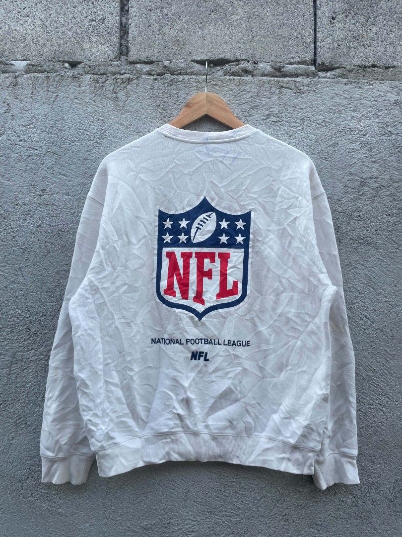 NFL Team Apparel White Crewneck Sweatshirt Medium (Category: Coats, Jackets and Outerwear) located in Banga. Submitted by its.zayn11e (Listing ID 1468713068, Image 1). Description: - Brand/Style: NFL Team Apparel off-white crewneck sweatshirt - Size: Medium - Design: Large NFL shield graphic on the back, small front chest logo, and woven tag near the bottom hem - Details: Classic ribbed cuffs, collar, and hem - Perfect for casual streetwear and g
