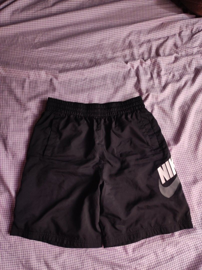 Nike Black Woven Shorts (Category: Shorts) located in Batangas. Submitted by astrofinds_ (Listing ID 1468717521, Image 1). Description: - Brand: Nike - Dimes: Waistline 26-34 / Length 18.5 / Hem - 11 - Size: XL (Made in Thailand) - Material: 100% polyester body and lining with lightweight mesh interior - Waistband: Elastic with comfortable stretch - Features: Large white Nike swoosh and lettering logo on left leg, plus convenient side pockets.