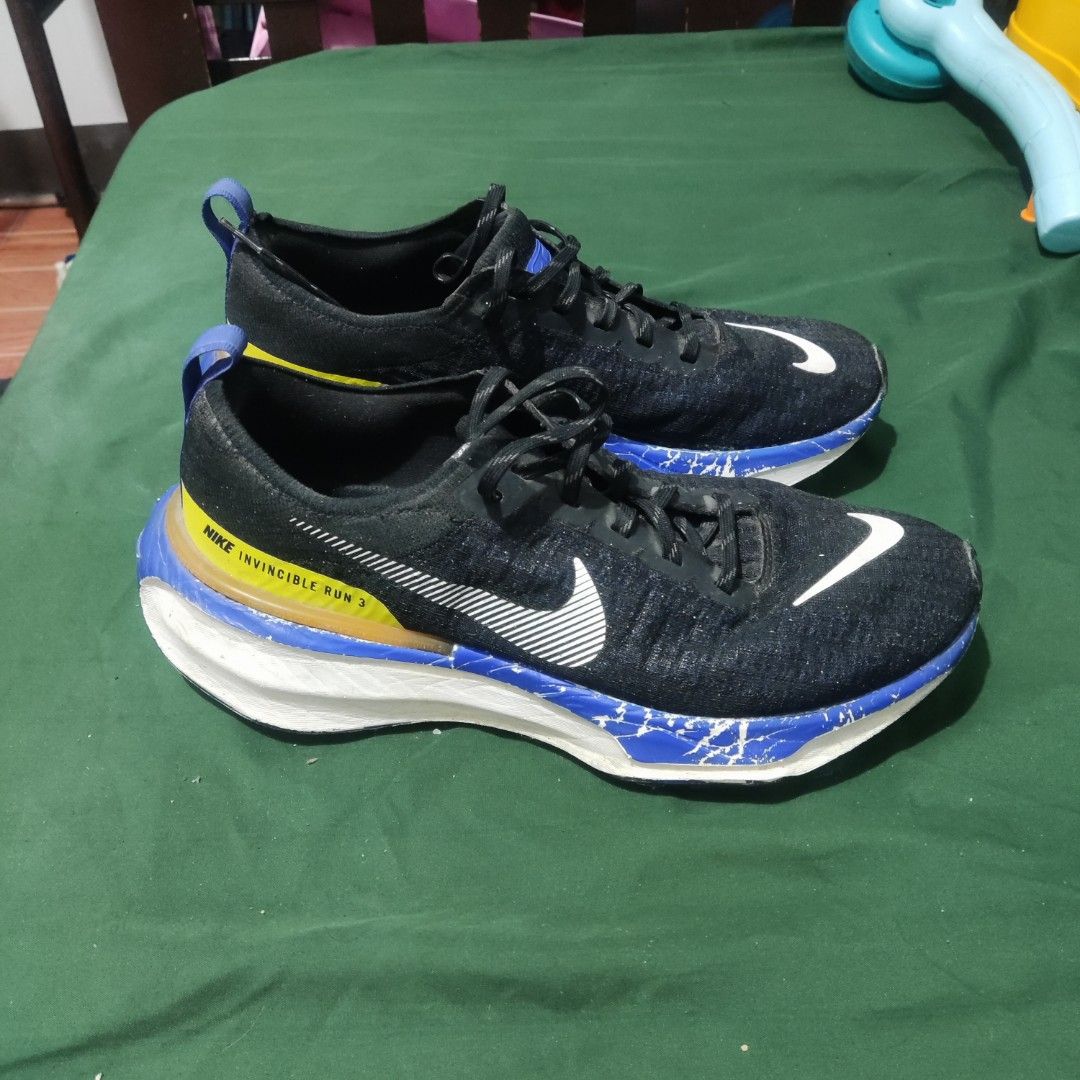 Nike Invincible Run 3 Black Blue Yellow (Category: Sneakers) located in San Mateo. Submitted by sweetys_closet (Listing ID 1468798797, Image 1). Description: Nike Invincible Run 3 running shoes. Black upper with white swoosh branding, accented with striking blue and yellow details on the heel and midsole. Thick cushioning for daily miles. Shows noticeable scuffs and paint chipping along the blue foam midsole section. Laces intact, soles have norm