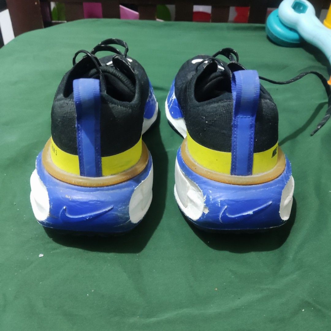 Nike Invincible Run 3 Black Blue Yellow (Category: Sneakers) located in San Mateo. Submitted by sweetys_closet (Listing ID 1468798797, Image 2). Description: Nike Invincible Run 3 running shoes. Black upper with white swoosh branding, accented with striking blue and yellow details on the heel and midsole. Thick cushioning for daily miles. Shows noticeable scuffs and paint chipping along the blue foam midsole section. Laces intact, soles have norm