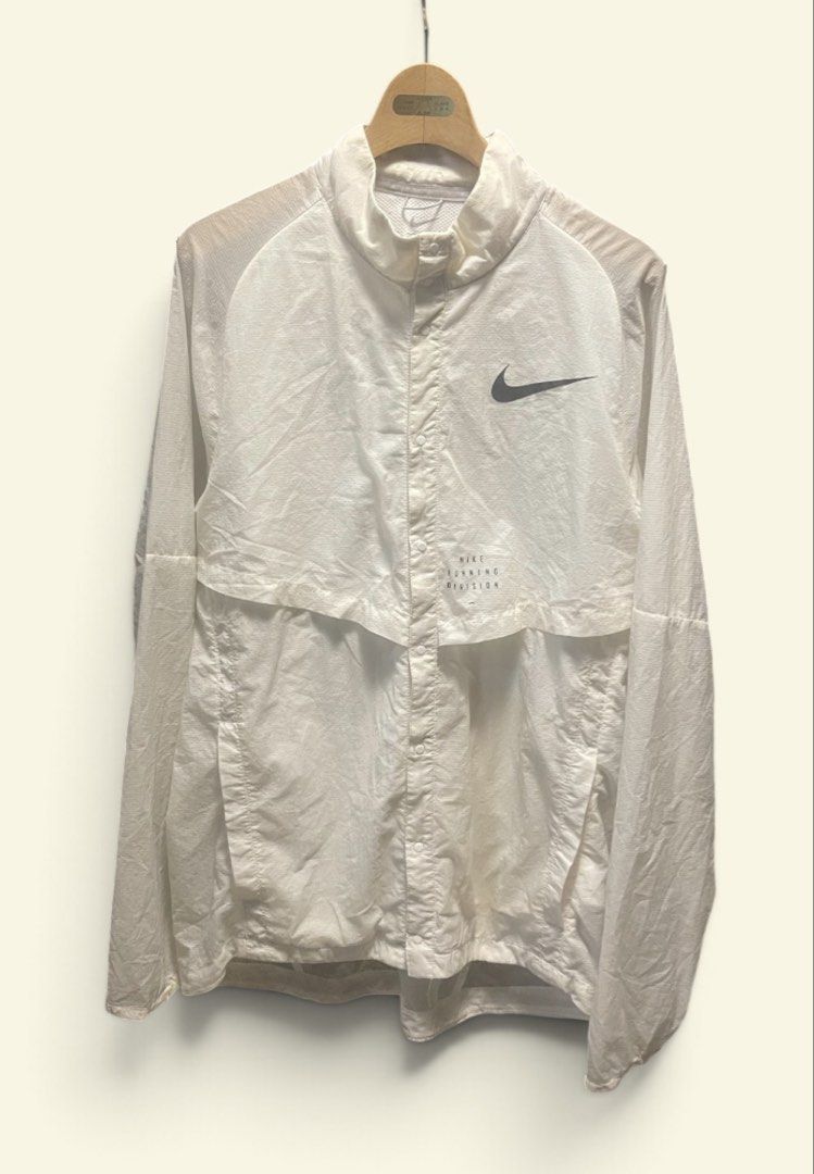 Nike Running Division White Windbreaker Packable Jacket Unisex (Category: Coats, Jackets and Outerwear) located in San Pedro. Submitted by lifebeginsaftercoff33 (Listing ID 1468809521, Image 3). Description: - Authentic Nike Running Division jacket in white Unisex -Packable garment - Classic snap-button front closure with high collar - Two side pockets - Nike swoosh logo on chest with additional text branding - Lightweight, durable ripstop fabric