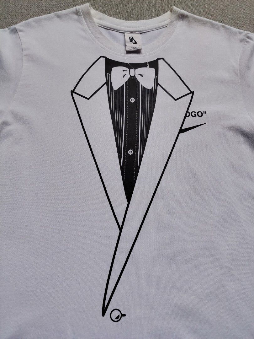 Nike x Off White NRG Shirt (Category: Tshirts & Polo Shirts ) located in Taguig. Submitted by _theroom.ph (Listing ID 1468752259, Image 3). Description: - Brand: Nike x Off-White - Color: White - Size: Medium (Made in China) - Front: Tuxedo & bow tie illustration with partial Swoosh - Back: Large bald eagle graphic, 'LOGO' text, and Nike Swoosh - Lower Back: Off-White for Nike Beaverton, Oregon USA text with c. 2017 date - Condition: Brand new / 