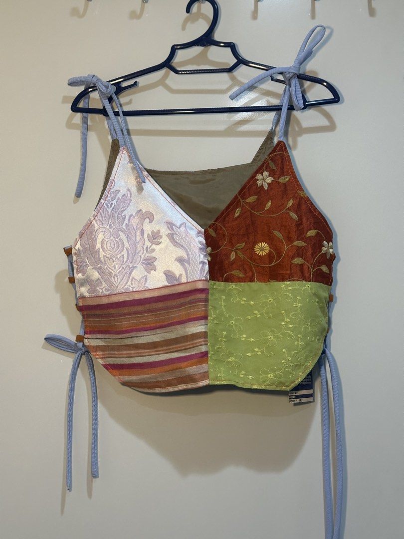 Nin & Yang Patchwork Lace-Up Crop Top M-L (Category: Sleeveless) located in Taguig. Submitted by ellajanee (Listing ID 1468767461, Image 3). Description: - Nin & Yang patchwork crop top - Multi-colored panels with orange, purple, green, and pink floral patterns - Size M-L tag attached - Adjustable tie straps at the shoulders - Side lace-up loops for a customizable fit - Unique handmade style and vibrant color combination.