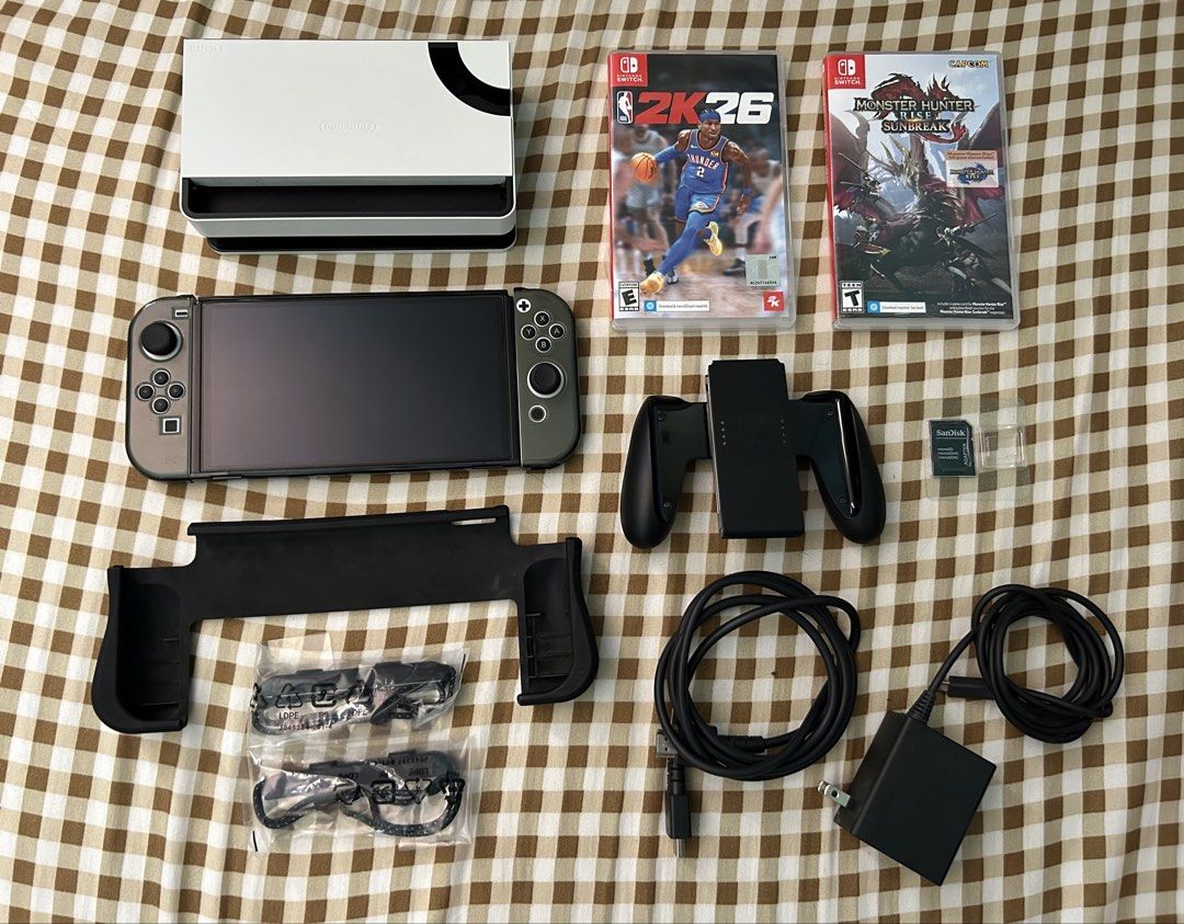 Nintendo Switch OLED Model with Games and Accessories (Category: Nintendo) located in Manila. Submitted by creed.808 (Listing ID 1468731446, Image 2). Description: - Nintendo Switch OLED Console (White & Grey Joy-Cons) - Complete original accessories: Dock, power adapter, HDMI cable, and Joy-Con grip (Skull and Co) thumb grips - 2 Physical Games: NBA 2K26 and Monster Hunter Rise Sunbreak - SanDisk microSD card with adapter included - Extras: Blac