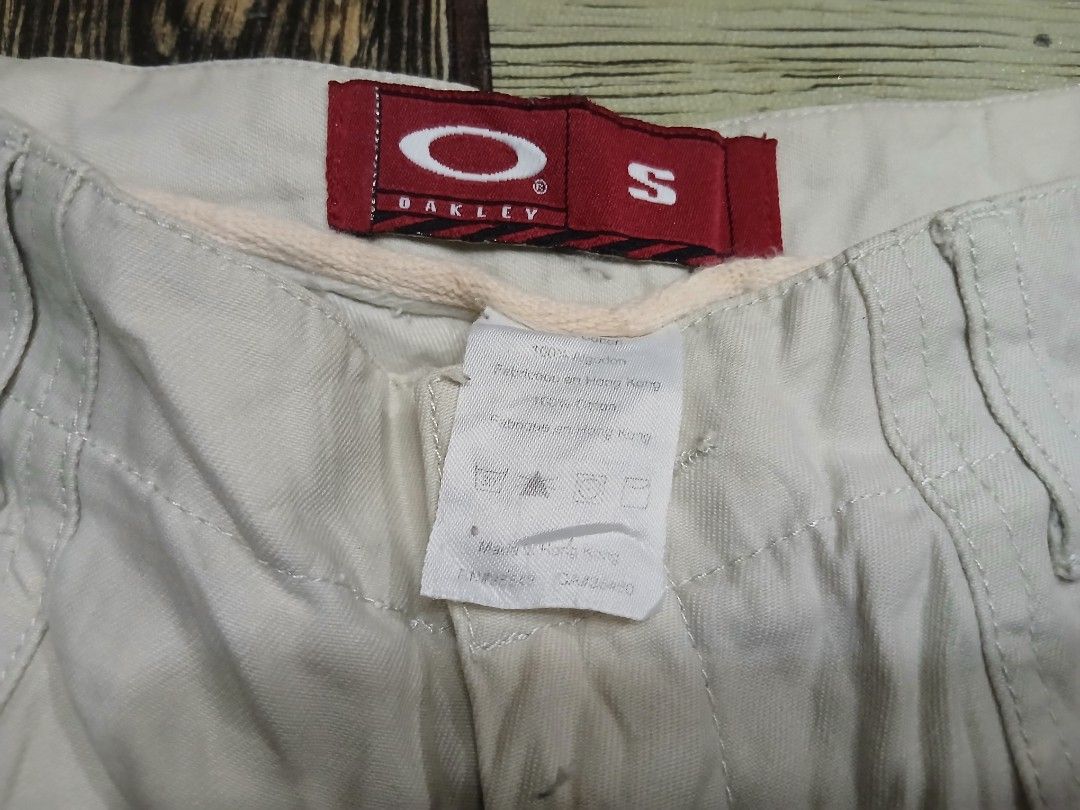 Oakley Beige Shorts Size S (Category: Shorts) located in Caloocan City. Submitted by youngmoon_51e2c6 (Listing ID 1468792917, Image 3). Description: - Brand: Oakley - Color: Beige - Size: Small (S) - Style: Classic utility shorts with button closure and belt loops - Details: Front patch pockets, embroidered Oakley logo near the hem, red brand label inside, and small red tag on the back pocket - Material: 100% Cotton - Origin: Made in Hong Kong.