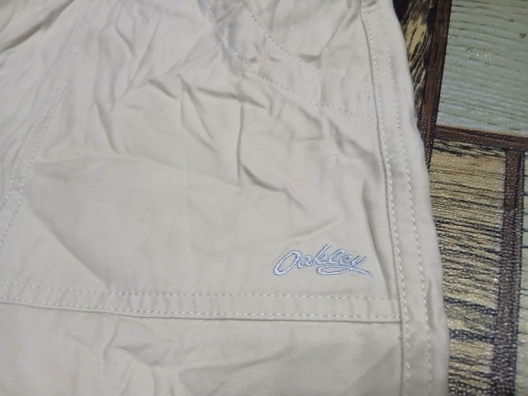 Oakley Beige Shorts Size S (Category: Shorts) located in Caloocan City. Submitted by youngmoon_51e2c6 (Listing ID 1468792917, Image 2). Description: - Brand: Oakley - Color: Beige - Size: Small (S) - Style: Classic utility shorts with button closure and belt loops - Details: Front patch pockets, embroidered Oakley logo near the hem, red brand label inside, and small red tag on the back pocket - Material: 100% Cotton - Origin: Made in Hong Kong.