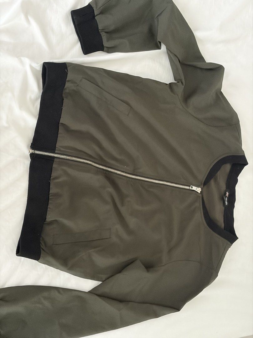 Olive Green Bomber Jacket Size M (Category: Coats, Jackets and Outerwear) located in Las Pinas. Submitted by thriftedfinds_ (Listing ID 1468829185, Image 2). Description: - Brand/Model: MC Michel Bomber Jacket - Color: Olive green with black ribbed collar, cuffs, and hem - Size: Medium - Closure & Pockets: Front zip closure with two side welt pockets - Fabric: Lightweight material, ideal for simple everyday layering.