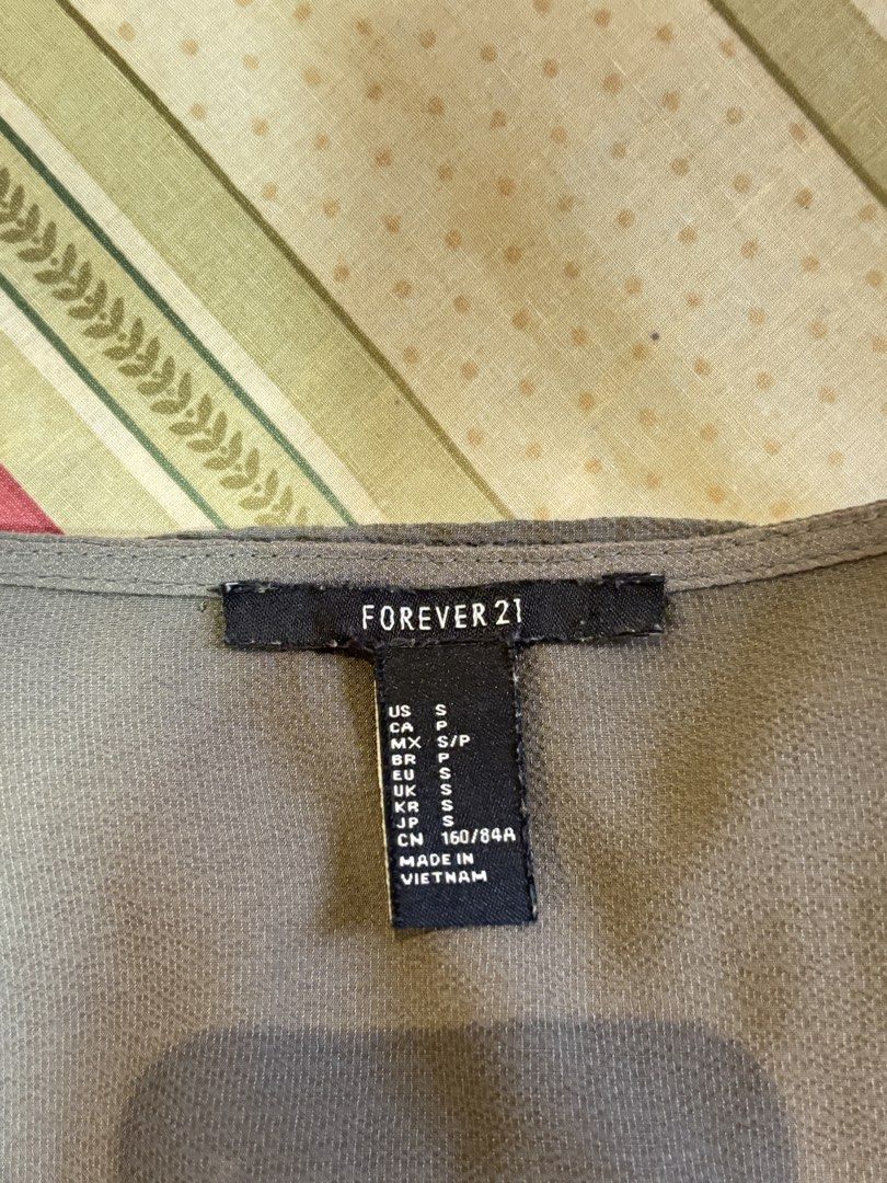 Olive Green Cross-Strap Wrap Blouse (Category: Blouses) located in Caloocan City. Submitted by joannarms320722 (Listing ID 1468781082, Image 2). Description: - Brand: Forever 21 - Size: S - Color: Olive green - Style: V-neck with criss-cross strap detail, wrap front, and draped hem - Sleeves: Long sleeves with buttoned cuffs - Fabric: Lightweight and comfortable - Condition: Worn only a couple of times, still in great shape - Styling tip: Easy to