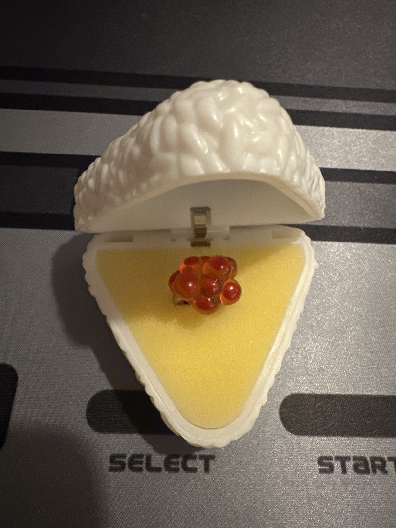 Onigiri Box Ring Salmon Roe gacha from japan (Category: Rings) located in Manila. Submitted by lunalux09 (Listing ID 1468717611, Image 1). Description: - Adorable salmon roe ring nestled in a realistic triangle rice ball case - Hinged case opens easily with a secure yellow foam insert - Fun and quirky accessory perfect for Japanese cuisine and miniature lovers - Great conversation piece and unique gift idea - Brand new, ships fast within the Phil