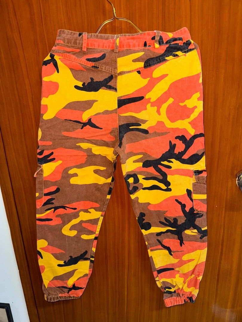 Orange Camo Cargo Pants Utility Joggers (Category: Joggers) located in Caloocan City. Submitted by mylove326 (Listing ID 1468794121, Image 2). Description: - Vibrant orange camo print (orange, yellow, brown, and black) - fit with secure button and zipper closure - Practical utility pockets on both sides - Trendy elastic cuffs at the ankles - Made from durable, sturdy cotton material - Ultimate streetwear statement piece - Please refer to the pict