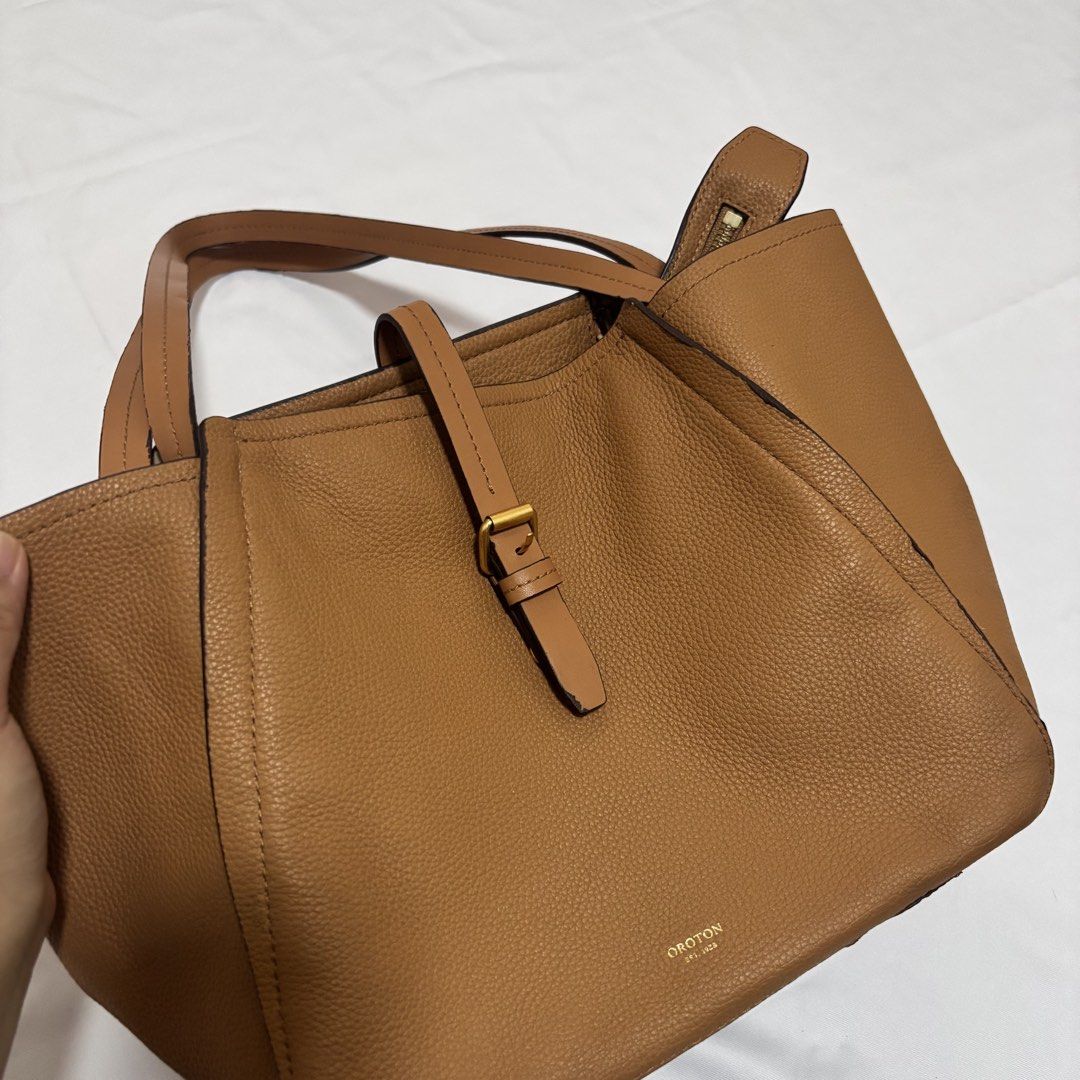 Oroton Tan Pebbled Leather Tote Bag (Category: Luxury Bags & Wallets) located in Imus. Submitted by wear.arca (Listing ID 1468826041, Image 2). Description: - Brand: Oroton - Material: Tan pebbled leather with gold-tone hardware - Closure: Front buckle strap - Straps: Twin shoulder straps - Flaws: Noticeable scuffing on the handle edge and peeling along the inner lining trim (kindly check close-up photos before buying) - So spacious and body is s