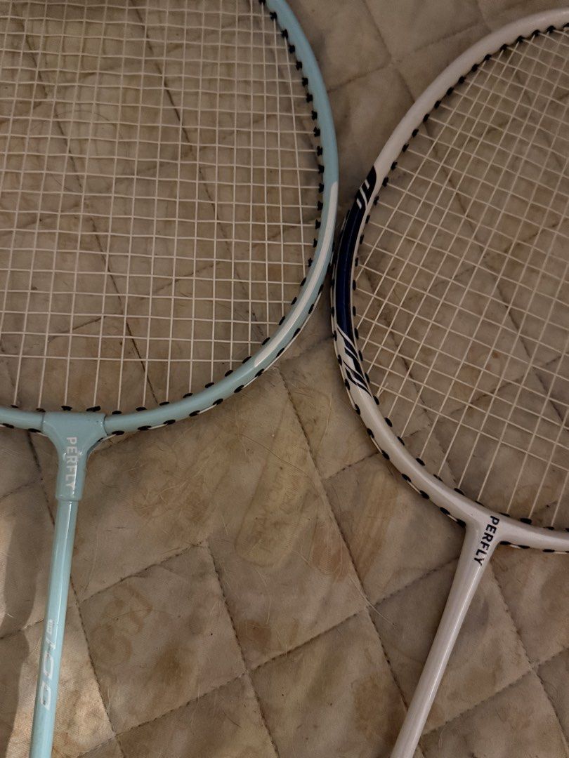 Perfly Badminton Rackets and Shuttlecocks (Category: Racket and Ball Sports) located in Mandaluyong City. Submitted by ohayouclub (Listing ID 1468853880, Image 2). Description: - Set includes 2 Perfly badminton rackets (light blue and white colorways) - Both handles freshly wrapped with black grip tape (shows wear, may need replacing) - Strings are fully intact and ready for play - Includes 1 full tube of Perfly FSC 100 duck feather shuttlecocks 