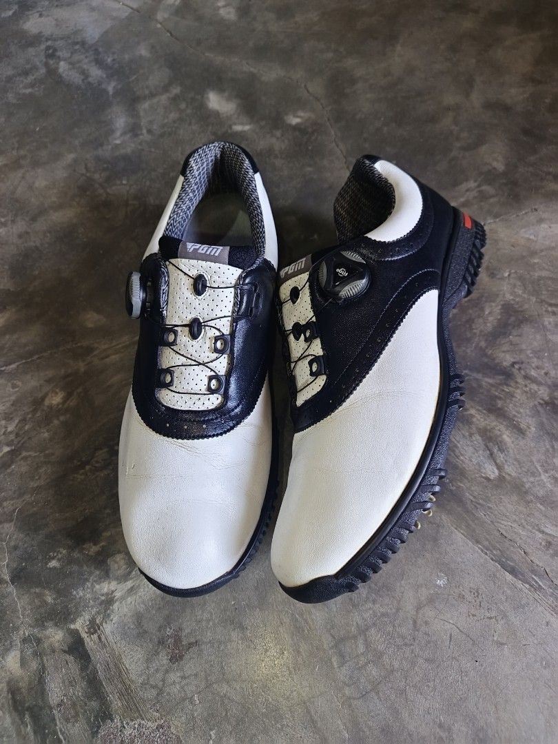 PGM Golf Shoes Size 45 (Category: Golf) located in Davao. Submitted by judethrifter (Listing ID 1468747699, Image 2). Description: - Brand: PGM Golf Shoes - Color: White and Black with a red stripe around the heel base - Size: USA 10 / UK 9 / EUR 45 - Closure: Quick-lace dial system for easy tightening - Soles: Spike soles with replaceable soft spikes for solid grip - Condition: Clean overall, with normal wear on the spikes from course use.