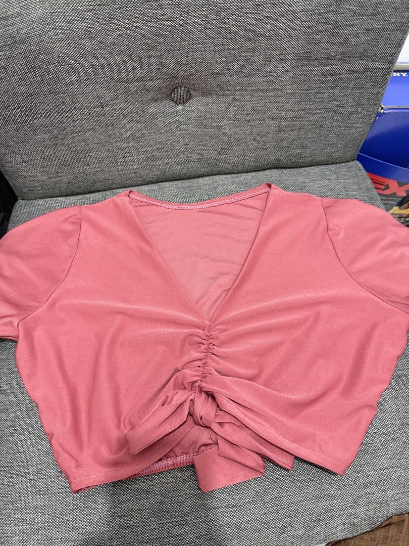 Pink V-Neck Crop Top (Category: Others Tops) located in Rodriguez. Submitted by prelovedbylalaine (Listing ID 1468928693, Image 1). Description: - Color: Dusty pink - Style: Casual crop top with short sleeves and deep V-neckline - Details: Center front ruched gathering with a tied knot - Fit: Stretchy elastic hem at the back for comfort - Fabric: Lightweight and breathable, perfect for pairing with high-waisted jeans or skirts.