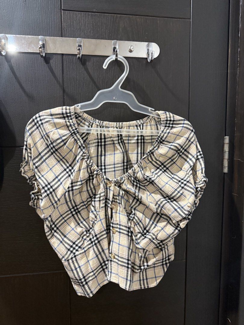 Plaid Crop Top Short Sleeve Button Front (Category: Shirts) located in Manila. Submitted by caeln (Listing ID 1468762234, Image 1). Description: - Style: Short sleeve crop top with classic black and blue plaid on a cream background - Details: V-neckline with gathered ruffles, center button-front with brown buttons, and puff sleeves - Fit: Elasticized cuffs and hem for a comfortable, fitted look - Fabric: Lightweight and breathable, perfect for wa
