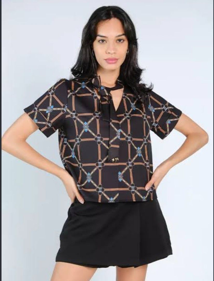 Plains and Prints Top (Category: Blouses) located in Iba. Submitted by geliqq (Listing ID 1468719888, Image 1). Description: - Style: Black short-sleeve blouse with chain and lattice pattern - Details: Cute neck tie at the collar - Fit: Relaxed and lightweight - Versatility: Easy to pair with skirts or trousers for work or casual wear - Condition: Clean and well-maintained.
