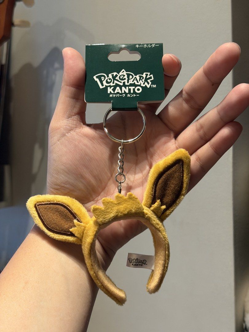PokéPark Kanto Eevee Ears Headband Keychain (Category: Character Goods) located in Santa Maria. Submitted by itsvener (Listing ID 1468745534, Image 1). Description: - Official PokéPark Kanto Eevee ears headband keychain - Made from soft, high-quality plush material in yellow and brown - Features the original official tag attached to the metal keyring - Includes inner fabric label with authentic branding - Clean metal split ring and chain link - R