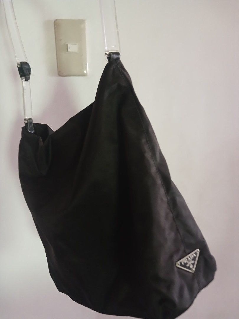 Prada Black Nylon Shoulder Bag with Clear Handles (Category: Luxury Bags & Wallets) located in Marikina City. Submitted by laila15 (Listing ID 1468922665, Image 2). Description: - Authentic black Prada shoulder bag made from signature lightweight nylon - Features stylish clear transparent handles secured with black leather tabs - Iconic silver-tone Prada triangle logo plaque on the side - Spacious, slouchy interior with secure zip closure - Condi