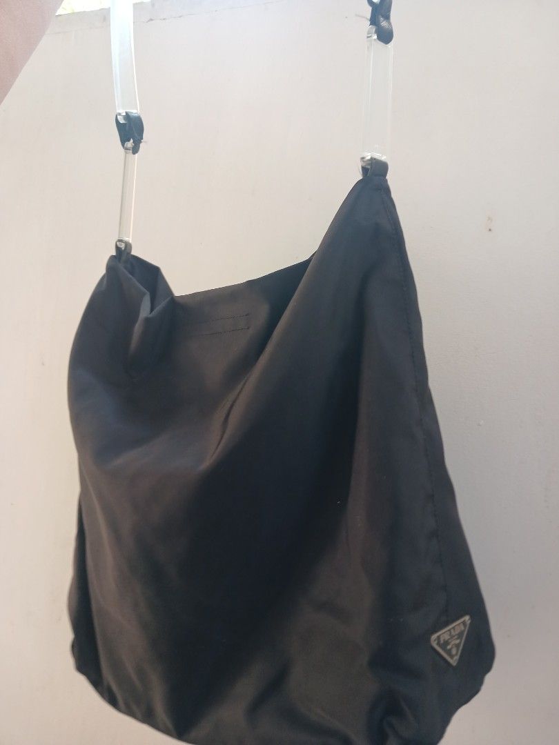 Prada Black Nylon Shoulder Bag with Clear Handles (Category: Luxury Bags & Wallets) located in Marikina City. Submitted by laila15 (Listing ID 1468922665, Image 3). Description: - Authentic black Prada shoulder bag made from signature lightweight nylon - Features stylish clear transparent handles secured with black leather tabs - Iconic silver-tone Prada triangle logo plaque on the side - Spacious, slouchy interior with secure zip closure - Condi