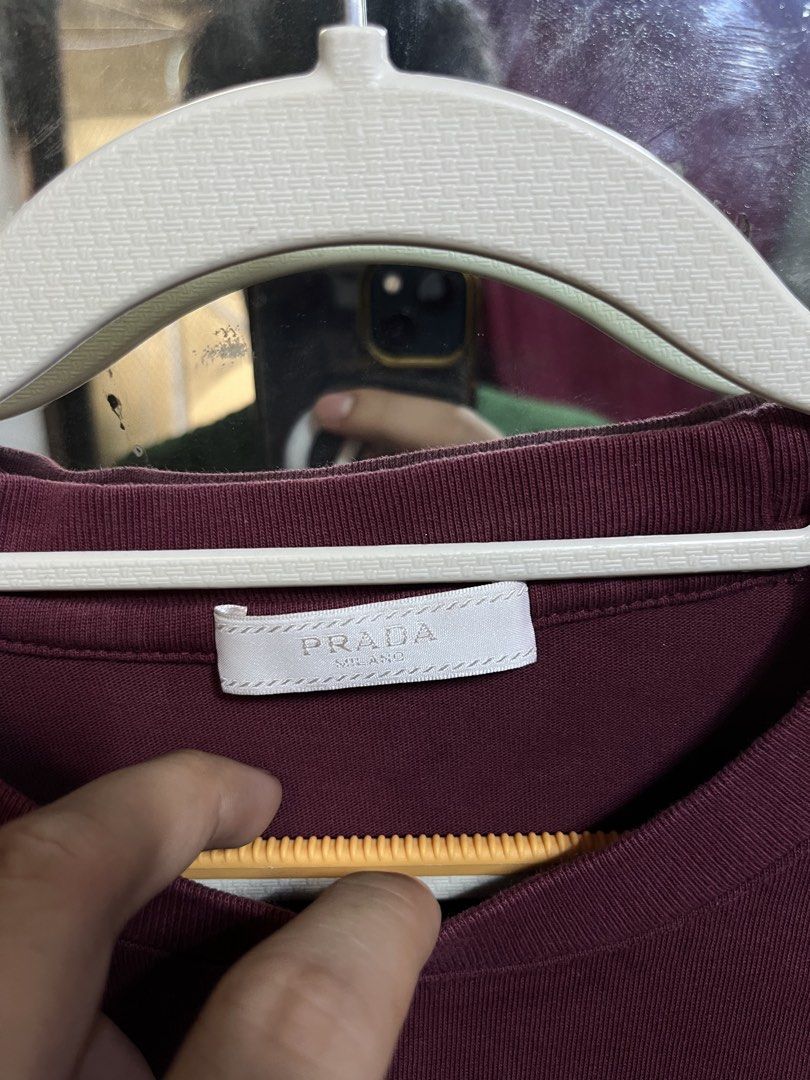 Prada Burgundy Triangle Logo T-Shirt Size M (Category: Shirts) located in Iloilo. Submitted by cloud.thrifts (Listing ID 1468802025, Image 2). Description: - Brand: Prada - Color: Burgundy - Material: 100% Cotton (Made in Italy) - Size: Medium (M) - Design: Short sleeves, crew neck, white triangular logo patch with distressed print - Condition: Excellent, comes with clean interior manufacturing and care tags.