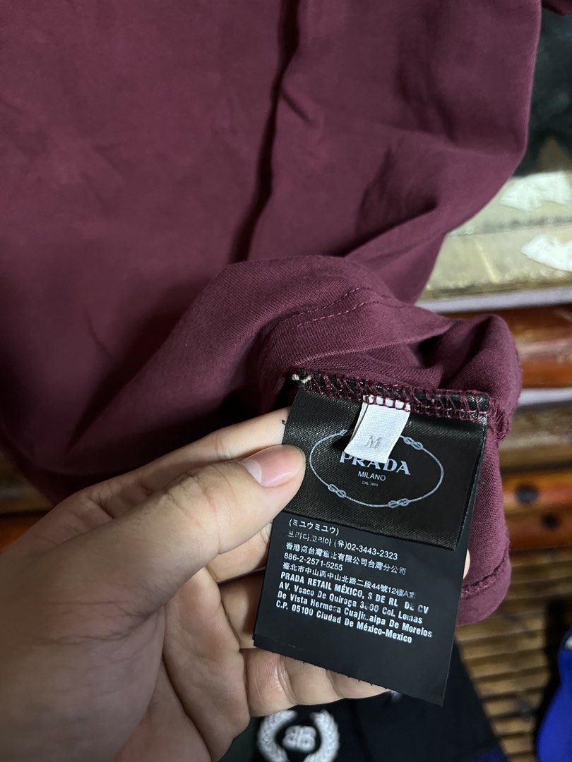 Prada Burgundy Triangle Logo T-Shirt Size M (Category: Shirts) located in Iloilo. Submitted by cloud.thrifts (Listing ID 1468802025, Image 3). Description: - Brand: Prada - Color: Burgundy - Material: 100% Cotton (Made in Italy) - Size: Medium (M) - Design: Short sleeves, crew neck, white triangular logo patch with distressed print - Condition: Excellent, comes with clean interior manufacturing and care tags.