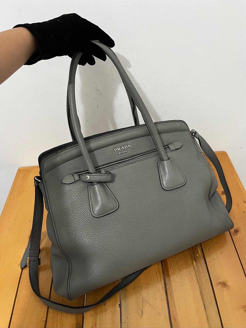 Prada Grey Leather Tote Handbag (Category: Luxury Bags & Wallets) located in San Fernando. Submitted by m_ang_0123 (Listing ID 1468810215, Image 1). Description: - Brand: Prada - Material: Premium pebbled leather in a versatile muted grey shade - Hardware: Sleek silver-tone with classic Prada Milano logo on front - Versatility: Includes double top handles and a detachable shoulder strap - Organization: Secure zip compartments for your daily essen