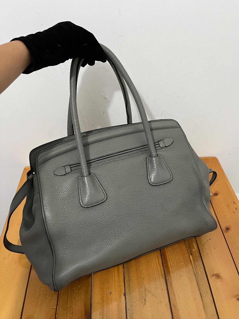 Prada Grey Leather Tote Handbag (Category: Luxury Bags & Wallets) located in San Fernando. Submitted by m_ang_0123 (Listing ID 1468810215, Image 3). Description: - Brand: Prada - Material: Premium pebbled leather in a versatile muted grey shade - Hardware: Sleek silver-tone with classic Prada Milano logo on front - Versatility: Includes double top handles and a detachable shoulder strap - Organization: Secure zip compartments for your daily essen