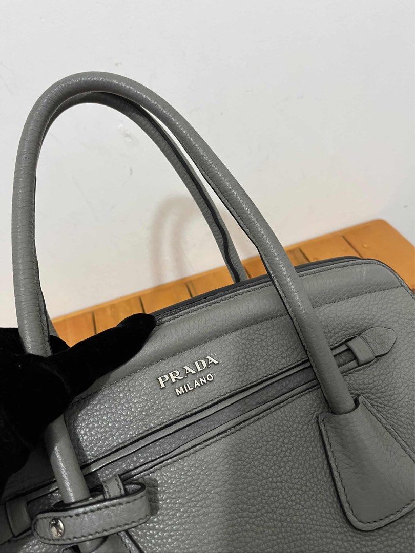 Prada Grey Leather Tote Handbag (Category: Luxury Bags & Wallets) located in San Fernando. Submitted by m_ang_0123 (Listing ID 1468810215, Image 2). Description: - Brand: Prada - Material: Premium pebbled leather in a versatile muted grey shade - Hardware: Sleek silver-tone with classic Prada Milano logo on front - Versatility: Includes double top handles and a detachable shoulder strap - Organization: Secure zip compartments for your daily essen