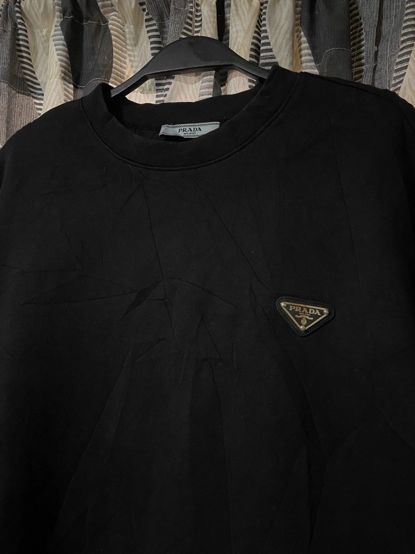 Prada Milano Black Triangle Logo Sweatshirt Size XL (Category: Coats, Jackets and Outerwear) located in Cebu City. Submitted by realfindz (Listing ID 1468815228, Image 2). Description: Prada Milano black crewneck sweatshirt in size XL. Features the iconic metal triangle logo plaque on the left chest. Ribbed collar, cuffs, and hem. Tag shows it was made in Moldova. Classic minimalist luxury piece that goes with everything. Grab it while it is avai