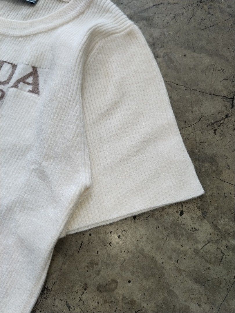 Prada Milano Knit T-Shirt White (Category: Shirts) located in Pasig City. Submitted by loveforlux_2025 (Listing ID 1468791467, Image 3). Description: - Color: White with brown Prada Milano knitted logo - Material: Soft, textured ribbed knit - Sleeves: Short sleeves - Neckline: Classic crew neck - Details: Authentic blue Prada brand label inside the collar.