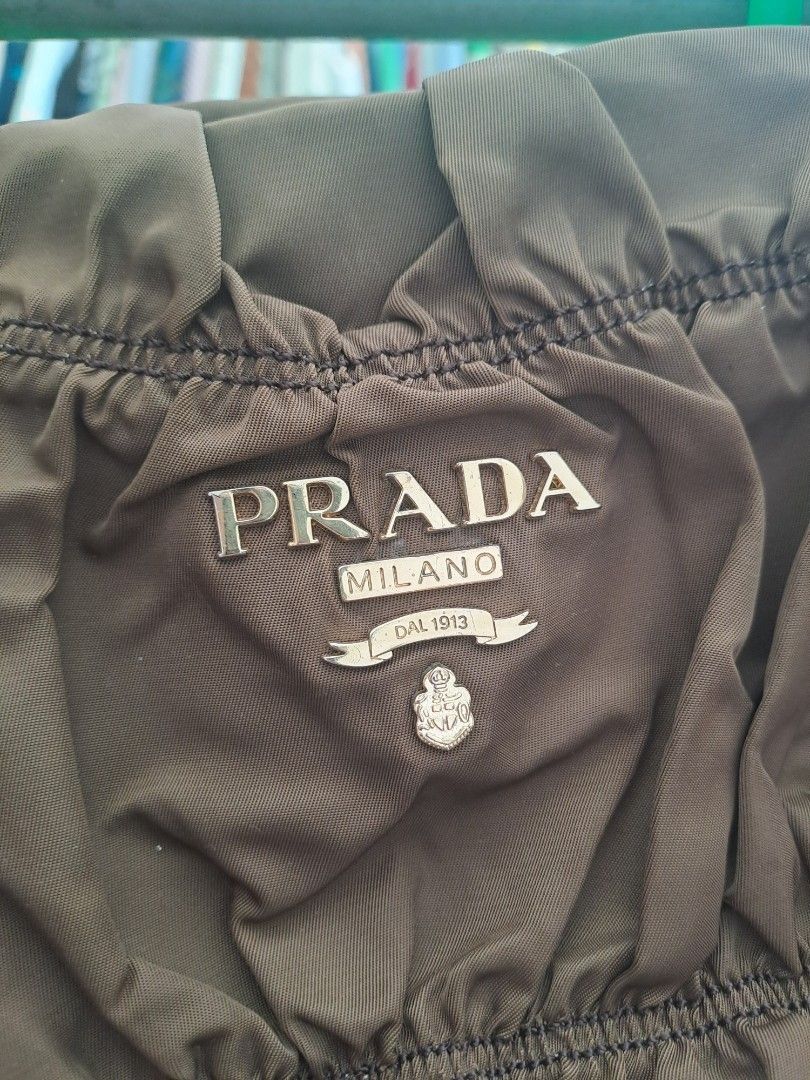 Prada Nylon Ruched Bag (Category: Luxury Bags & Wallets) located in Puerto Princesa. Submitted by jercksthriftph (Listing ID 1468928153, Image 2). Description: - Brand: Prada - Color: Rich brown - Material: Durable nylon with luxurious leather handles - Design: Stylish ruched exterior with iconic front logo plaque and matching leather key tag - Hardware: Elegant gold-tone accents - Interior: Signature Prada fabric lining with a convenient zippere