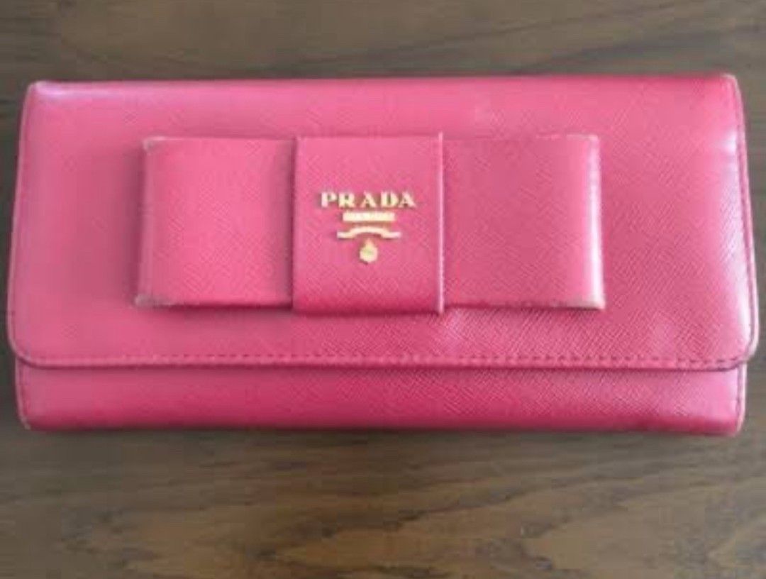 Prada Saffiano Flap Bow Wallet Pink (Category: Luxury Bags & Wallets) located in Manila. Submitted by asissaleh35322 (Listing ID 1468900745, Image 2). Description: - Brand: Prada - Material: Saffiano Leather - Color: Pink - Hardware: Gold-tone with front bow detail - Closure: Snap closure - Interior: Multiple card slots, compartments, and zipper coin pocket - Condition: Clean inside and out, minor wear around edges as shown in photos - Guaranteed