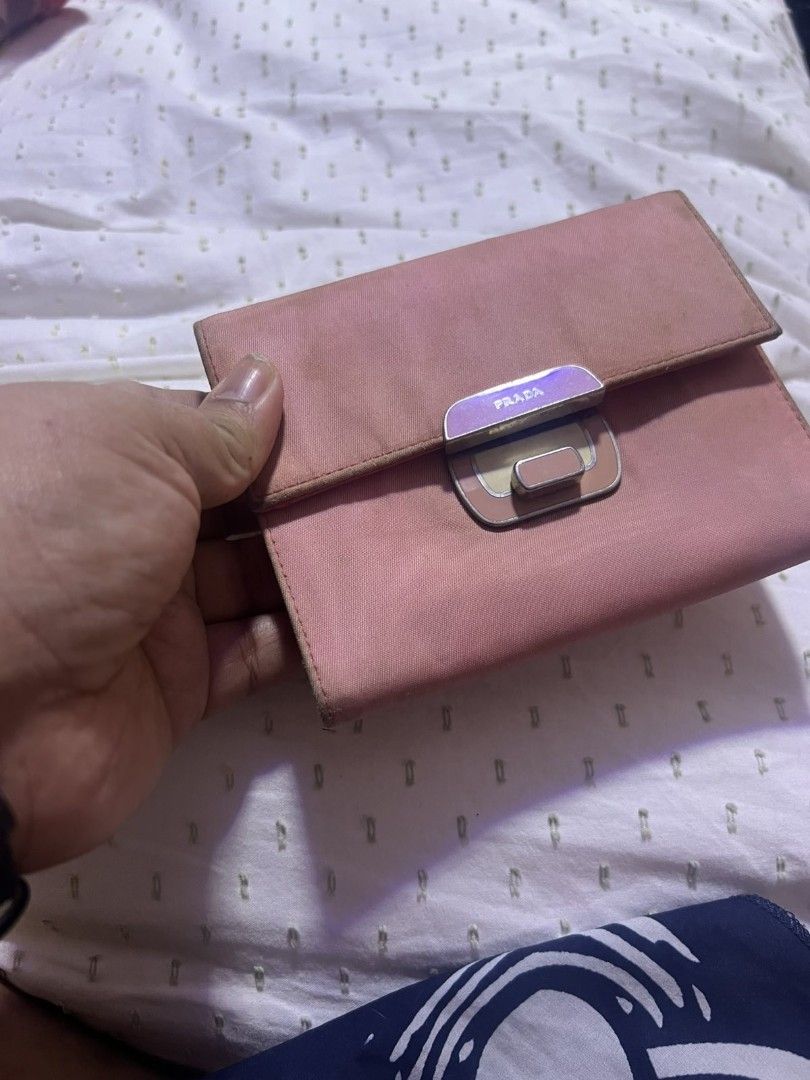 Prada Saffiano Leather Flap Wallet Pink (Category: Luxury Bags & Wallets) located in Manila. Submitted by asissaleh35322 (Listing ID 1468897765, Image 2). Description: - Authentic pink Prada wallet in durable Saffiano leather - Front metal lock clasp with engraved Prada branding - Interior includes multiple card slots, a bill compartment, and a coin pocket - Crafted in Italy (stamp visible inside) - Condition: Shows minor wear and scuffs on the e