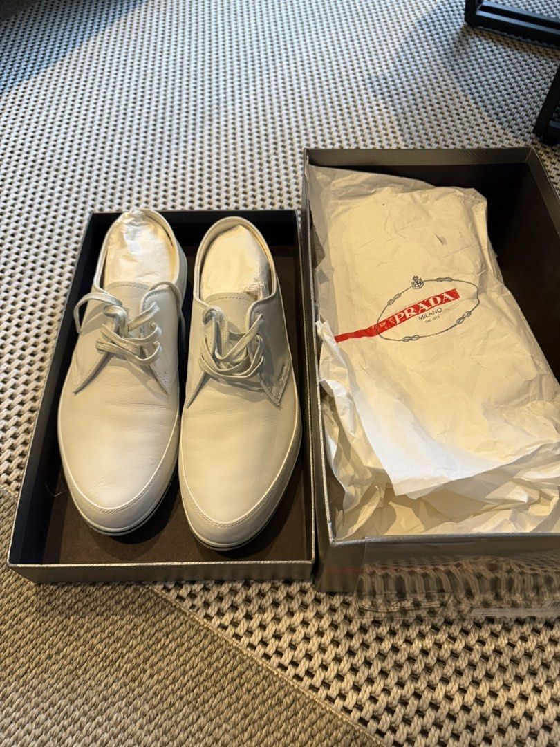 Prada White Leather Sneakers with Box (Category: Casual Shoes) located in Makati City. Submitted by marckyboy (Listing ID 1468748048, Image 1). Description: - Brand: Prada - Color: Crisp White - Material: Smooth premium leather - Design: Clean minimal aesthetic with classic lace-up front - Details: Flat rubber sole with black stripe detail and subtle debossed side logo - Inclusion: Comes inside original branded box with tissue paper - Condition: 