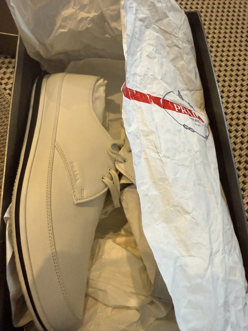 Prada White Leather Sneakers with Box (Category: Casual Shoes) located in Makati City. Submitted by marckyboy (Listing ID 1468748048, Image 2). Description: - Brand: Prada - Color: Crisp White - Material: Smooth premium leather - Design: Clean minimal aesthetic with classic lace-up front - Details: Flat rubber sole with black stripe detail and subtle debossed side logo - Inclusion: Comes inside original branded box with tissue paper - Condition: 