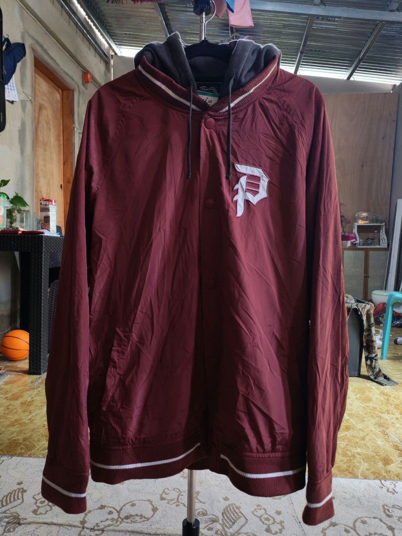 Primitive Maroon Hooded Bomber Jacket with White P Logo (Category: Coats, Jackets and Outerwear) located in Sipalay. Submitted by boldowl.e4f283 (Listing ID 1468772269, Image 1). Description: - Brand: Primitive - Color: Maroon with attached grey hoodie - Details: Large embroidered white 'P' logo on chest, striped ribbed cuffs, collar, and hem - Closure: Snap button front - Pockets: Convenient side pockets - Fit: Lightweight, ideal for layering - 