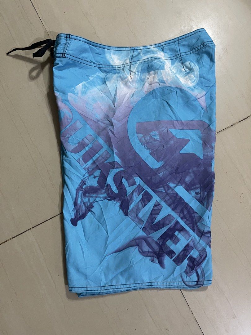 Quiksilver Blue Board Shorts Swim Trunks (Category: Swim Trunks & Board Shorts) located in Manila. Submitted by stuzzygod (Listing ID 1468856501, Image 2). Description: - Brand: Quiksilver -Size 34 - Length 22 - Leg open 12 - Color: Light blue with large purple smoke graphic print - Features: Single cargo pocket on the right leg with embroidered branding and eyelet drains - Waist: Drawstring waist closure with black lining - Origin: Made in Franc