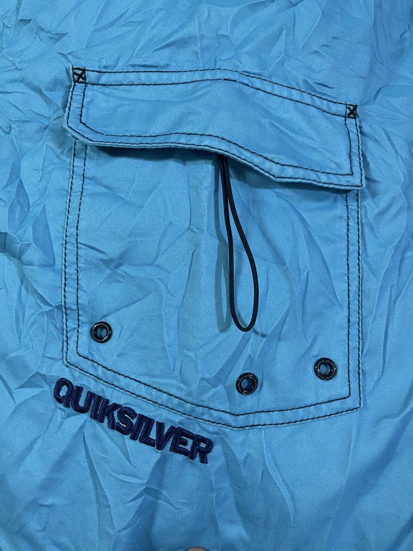 Quiksilver Blue Board Shorts Swim Trunks (Category: Swim Trunks & Board Shorts) located in Manila. Submitted by stuzzygod (Listing ID 1468856501, Image 3). Description: - Brand: Quiksilver -Size 34 - Length 22 - Leg open 12 - Color: Light blue with large purple smoke graphic print - Features: Single cargo pocket on the right leg with embroidered branding and eyelet drains - Waist: Drawstring waist closure with black lining - Origin: Made in Franc